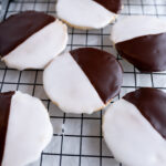 Textbook black and white cookies on a cooling rack.