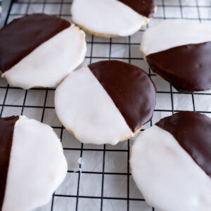 Textbook black and white cookies on a cooling rack.