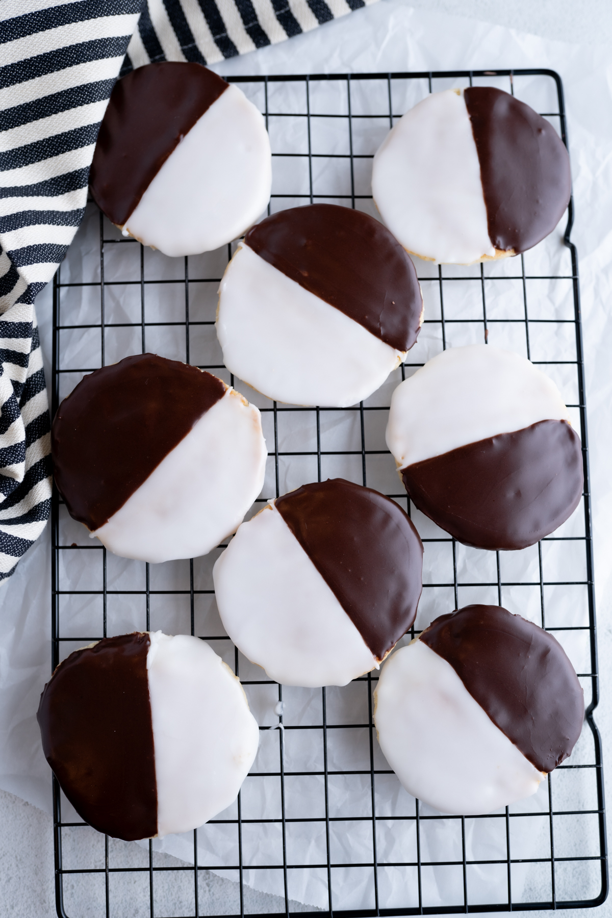 A cooling rack filled with flat-top black and white cookies. 
