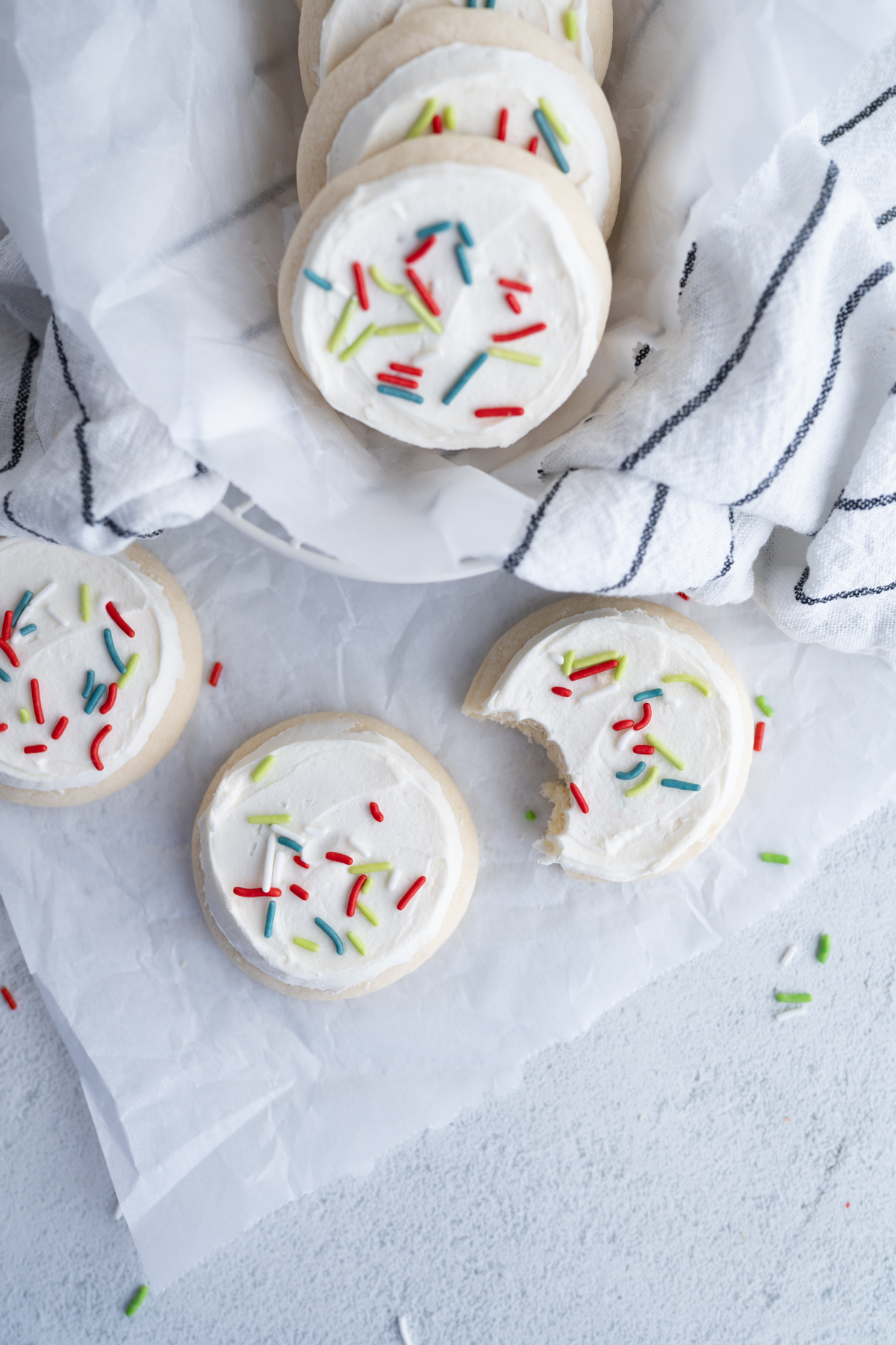 Aerial view of frosted sugar cookies on the counter. One cookie has a bite taken out of it. 