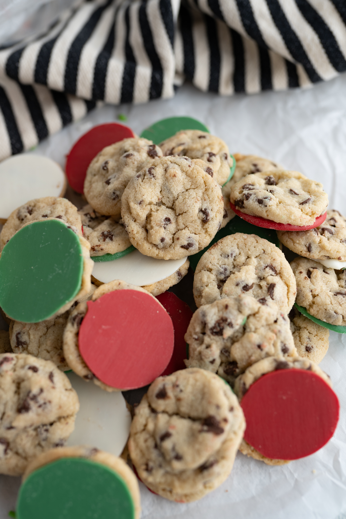 A pile of mini chocolate chip cookies dipped in christmas-colored chocolate. 