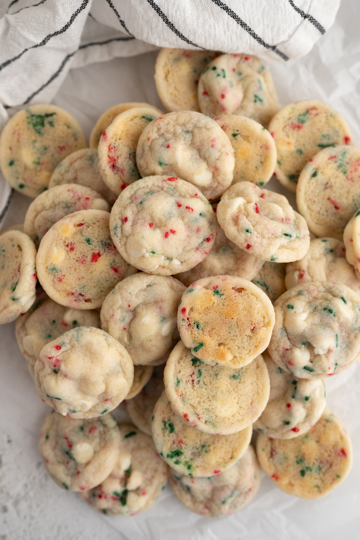 A pile of christmas sprinkle cookies with white chocolate chips.