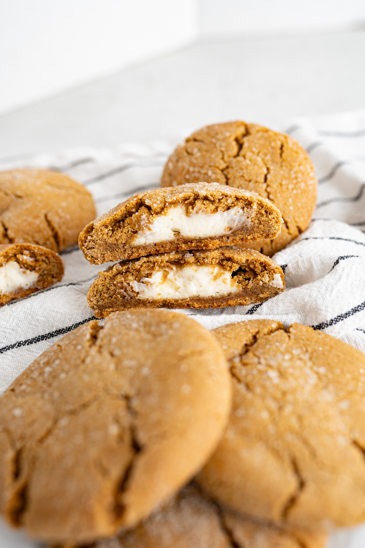 A pile of gingerbread cheesecake cookies on the counter. One cookie is cut in half and stacked. 