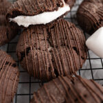 Close up of a hot cocoa bomb cookie stuffed with a marshmallow and drizzled with chocolate.