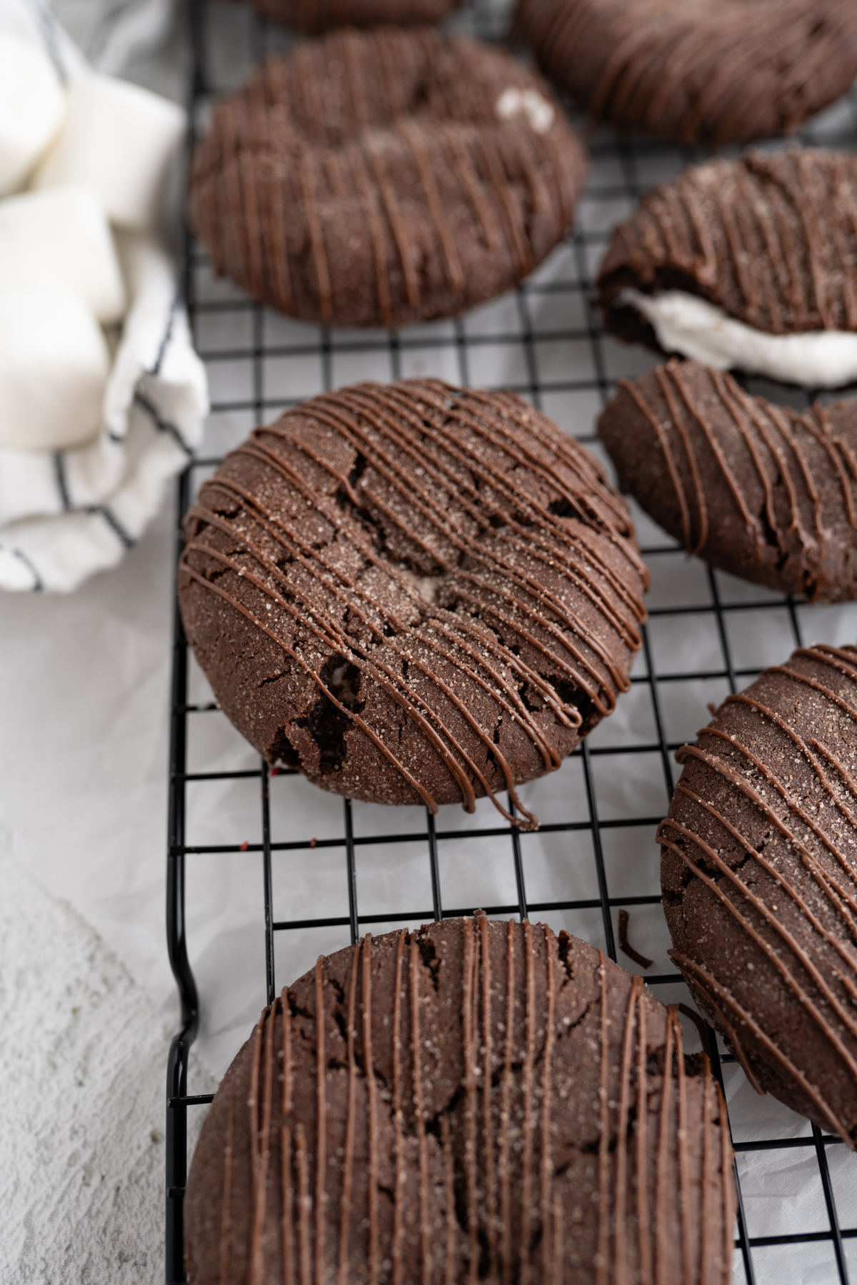 Hot cocoa bomb cookie drizzled with chocolate on a cooling rack. 