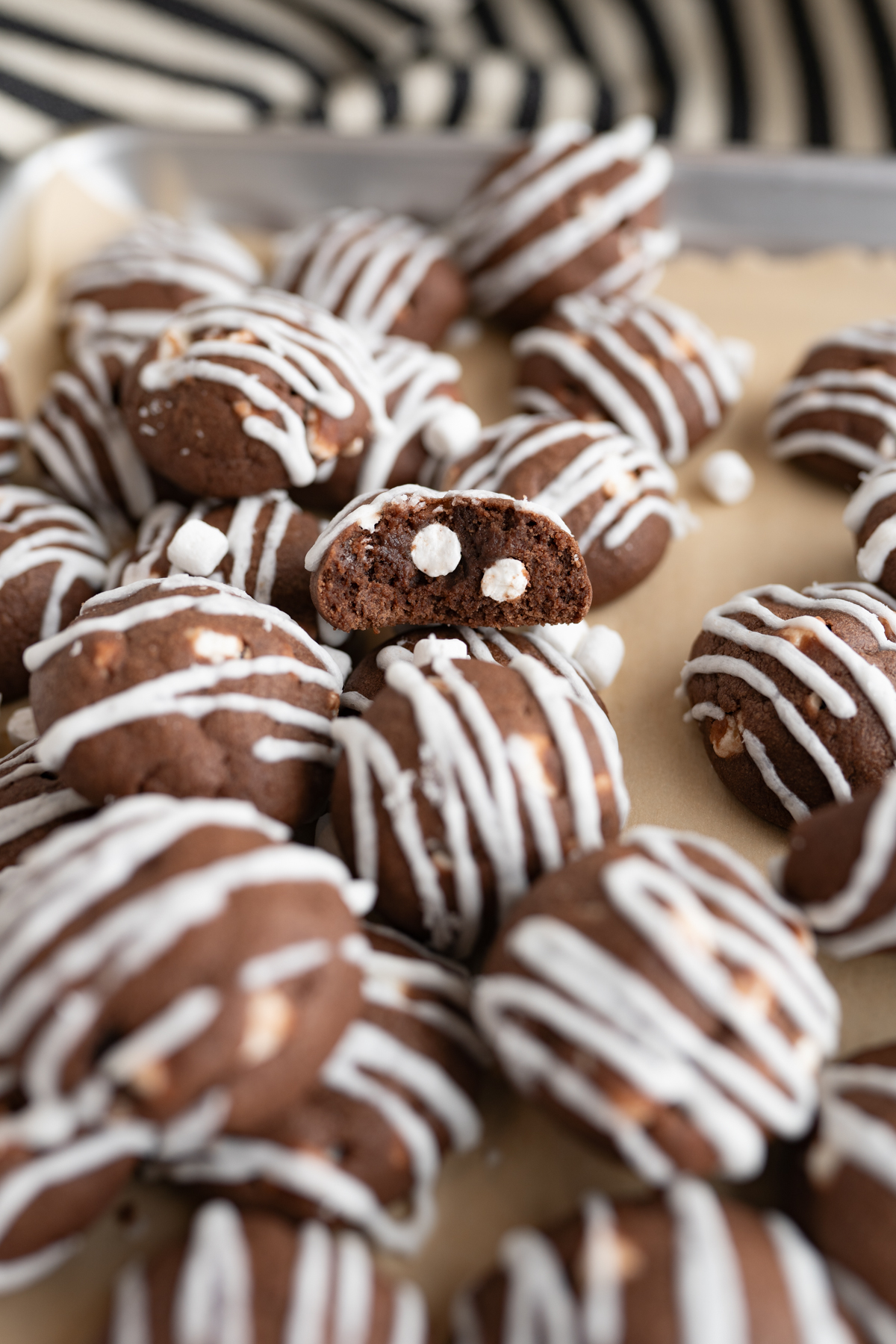 A hot cocoa cookie with a bite taken out of it to reveal marshmallows inside. 