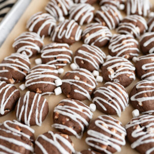 A tray filled with hot cocoa meltaway cookies drizzled with vanilla icing.