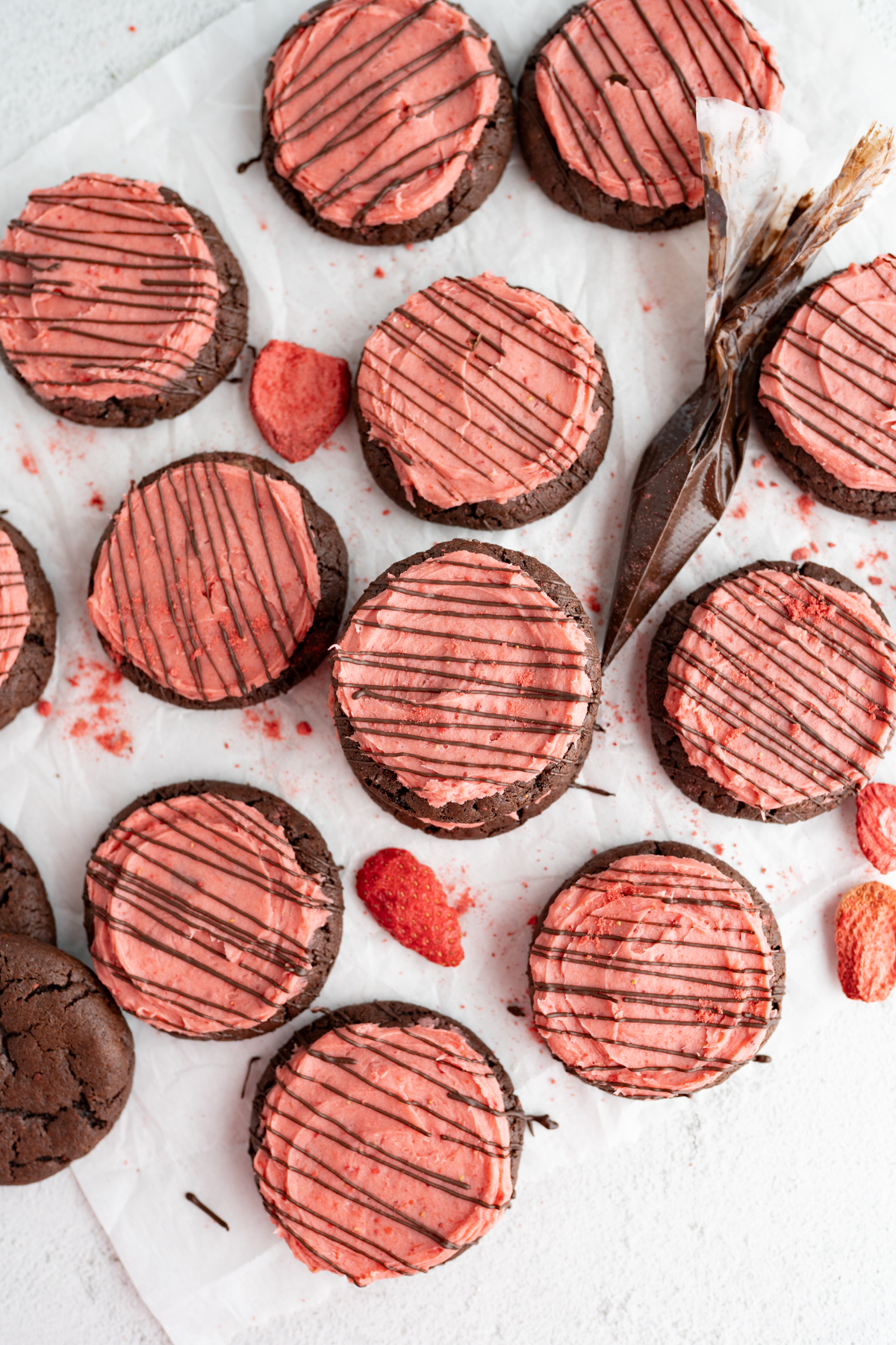 Aerial view of a bunch of frosted chocolate covered strawberry cookies. 