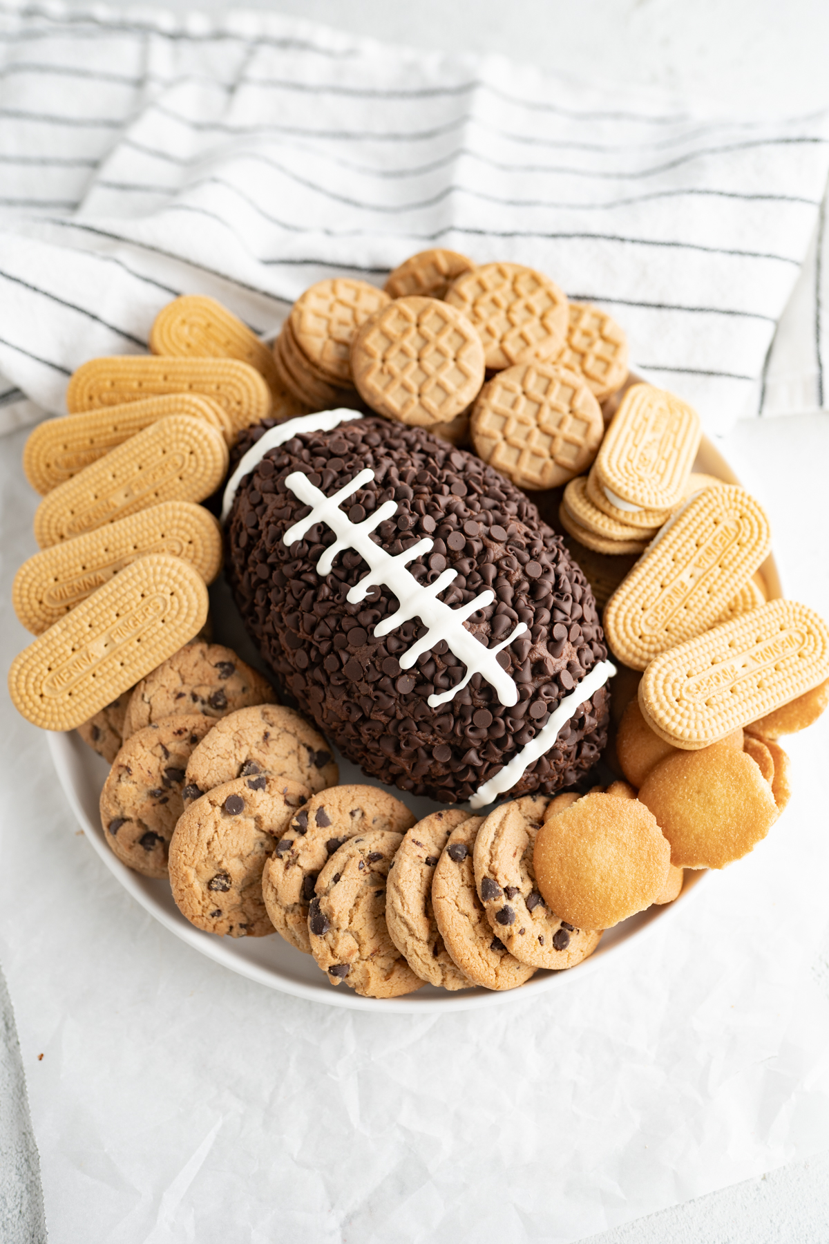 Aerial view of a chocolate cheeseball decorated like a football and surrounded by cookies to dip. 
