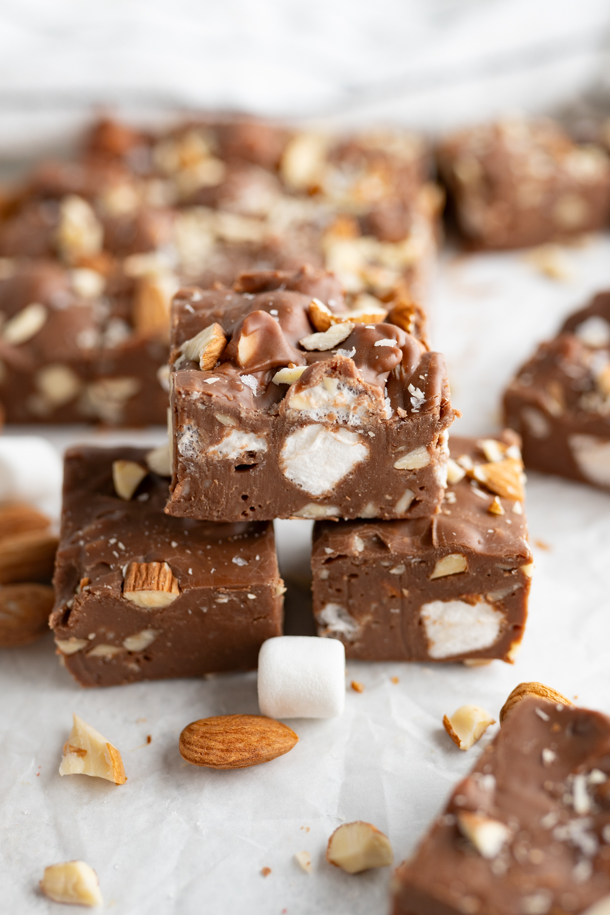 A side view of a stack of 3 rocky road fudge pieces.