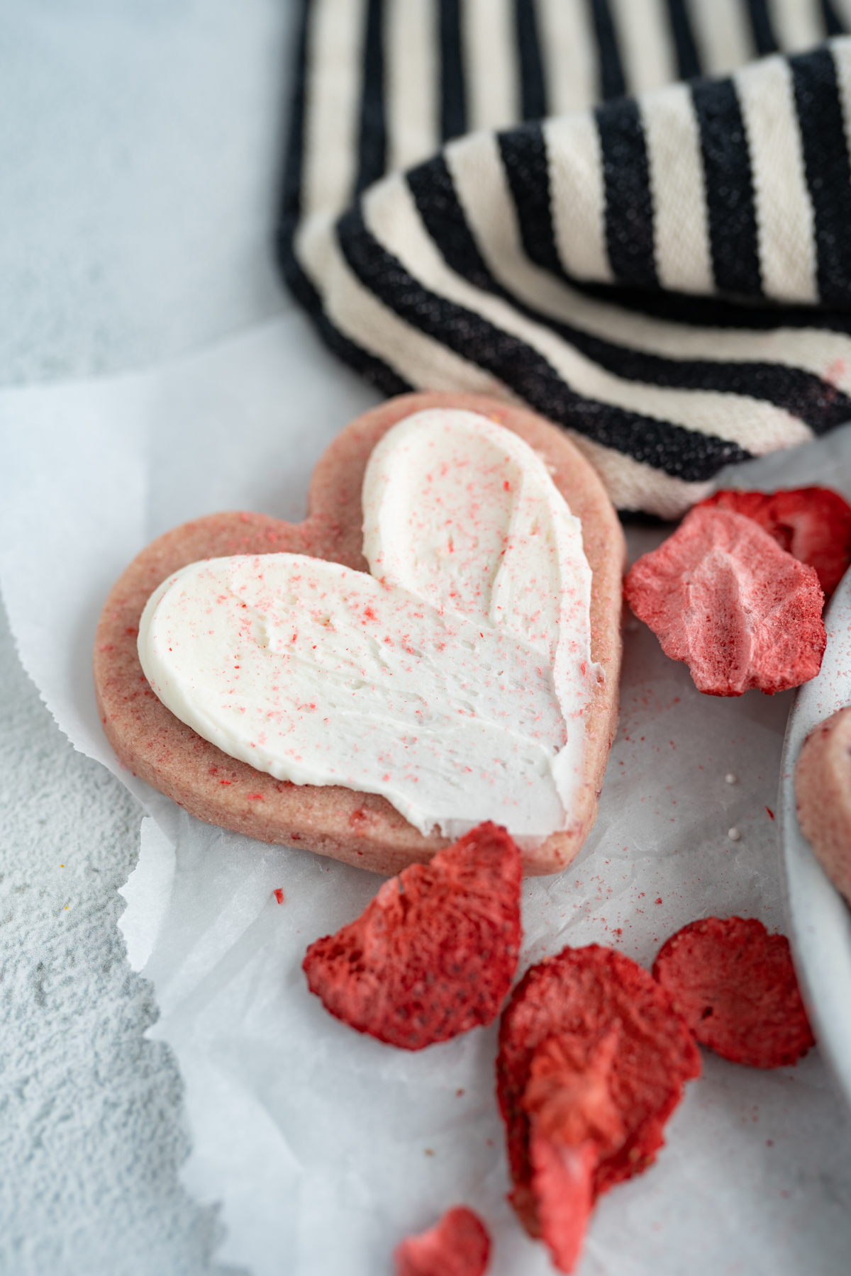 A frosted strawberry cookie next to freeze dried strawberries. 