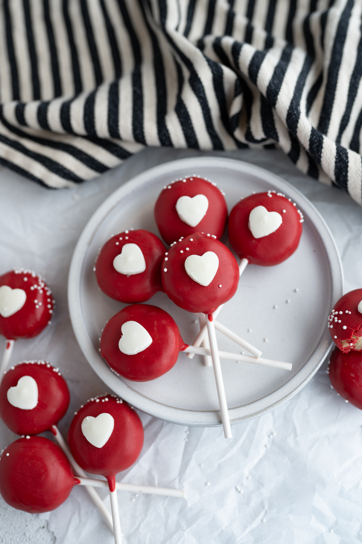 Aerial view of red valentine cake pops on a plate. 