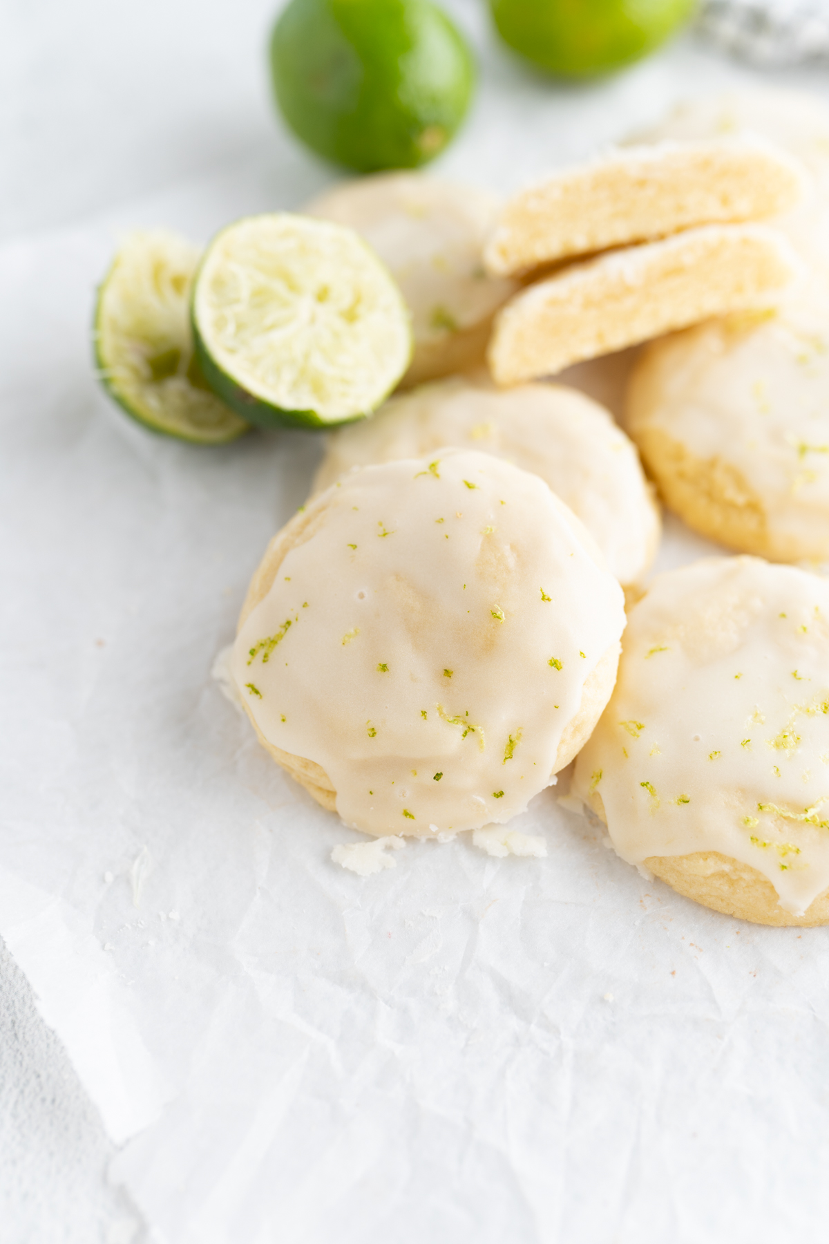 A pile of coconut lime cookies next to juiced limes. 