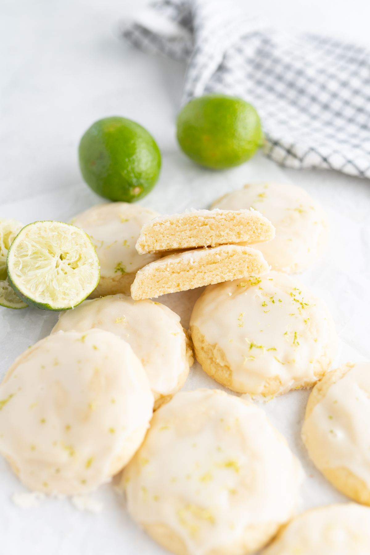 A pile of lime coconut cookies with the cookie cut in half to reveal a soft interior. 