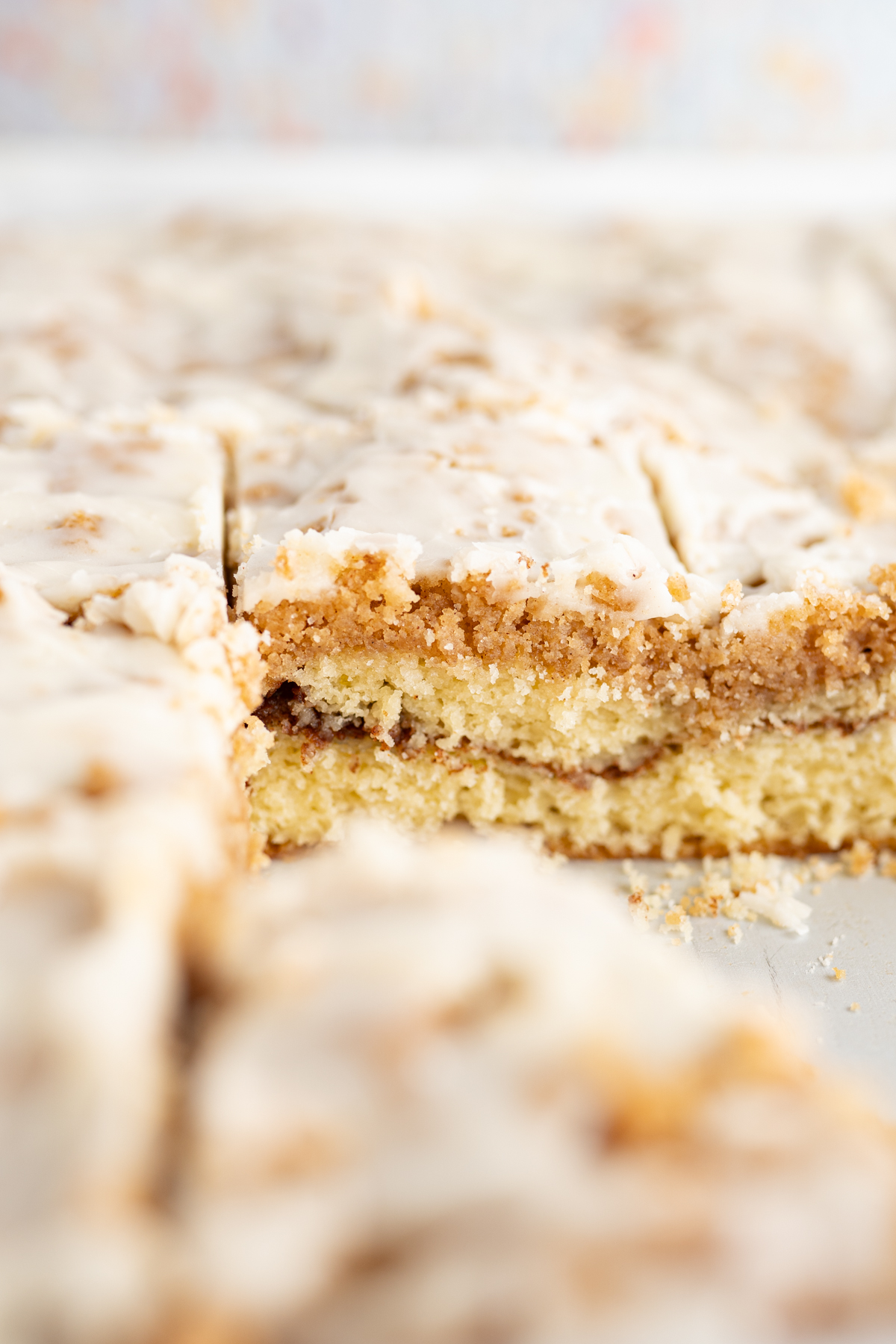 Side view of a pan of coffee cake topped with vanilla glaze.