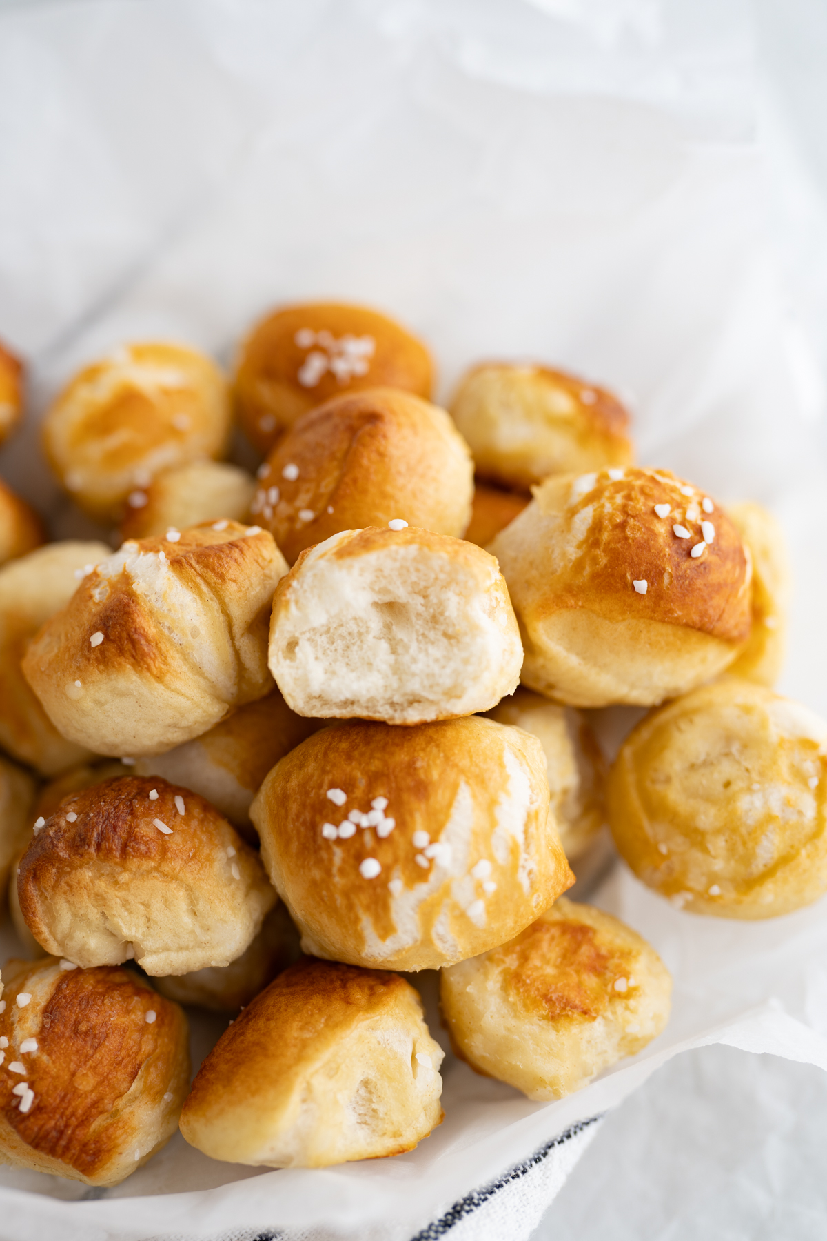 Close up of a pile of salted pretzel bites. The bite on top has a bite taken out of it to reveal the soft center.
