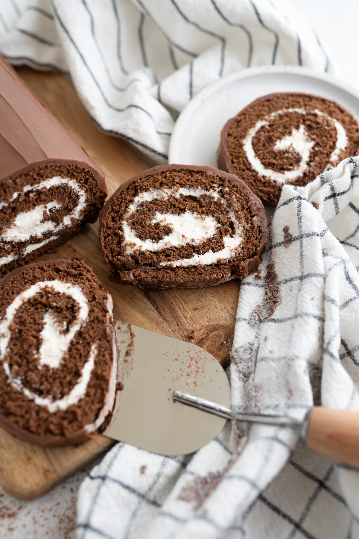 Multiple slices of swiss roll cake being served up. 