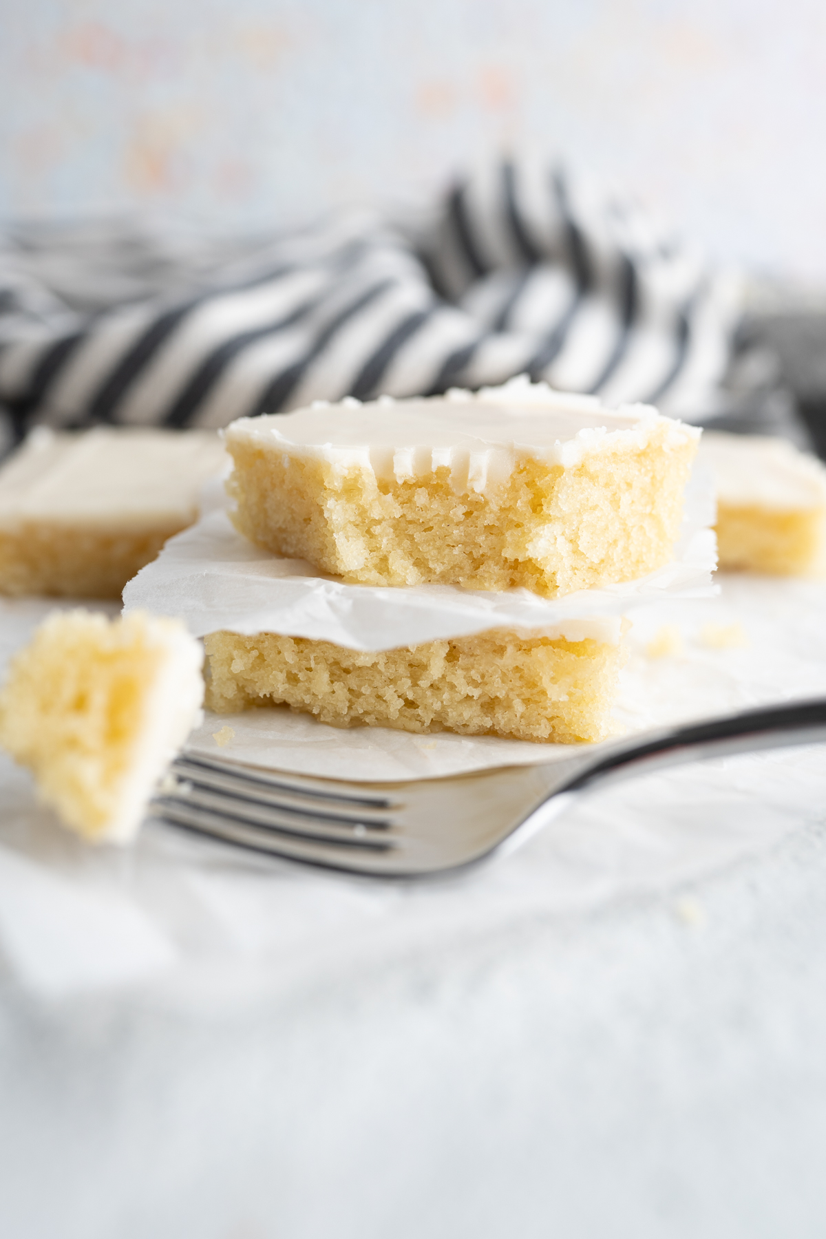 A slice of vanilla sheet cake with a forkful out of it. 