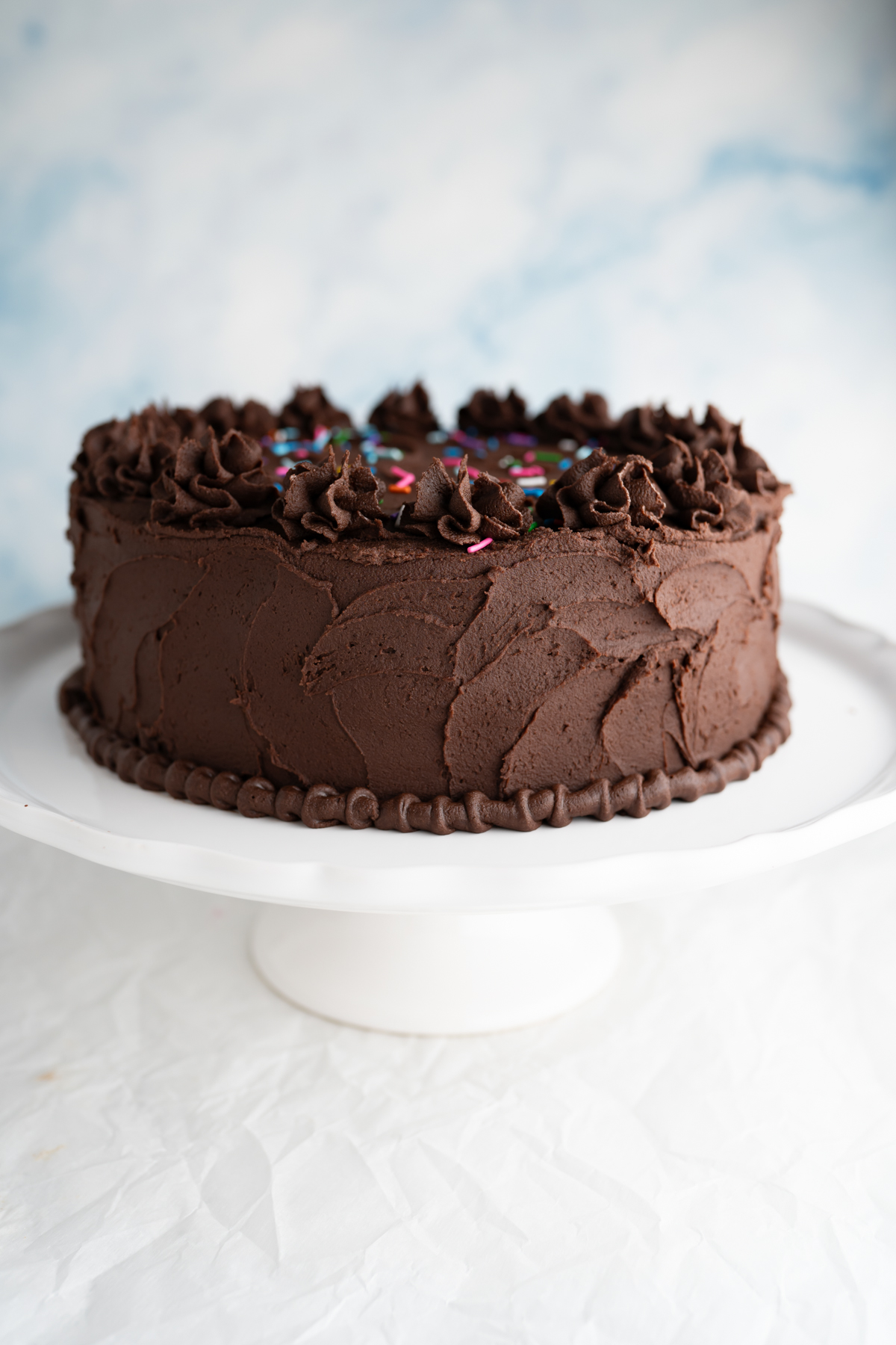 Side view of a chocolate birthday cake on a cake stand. 