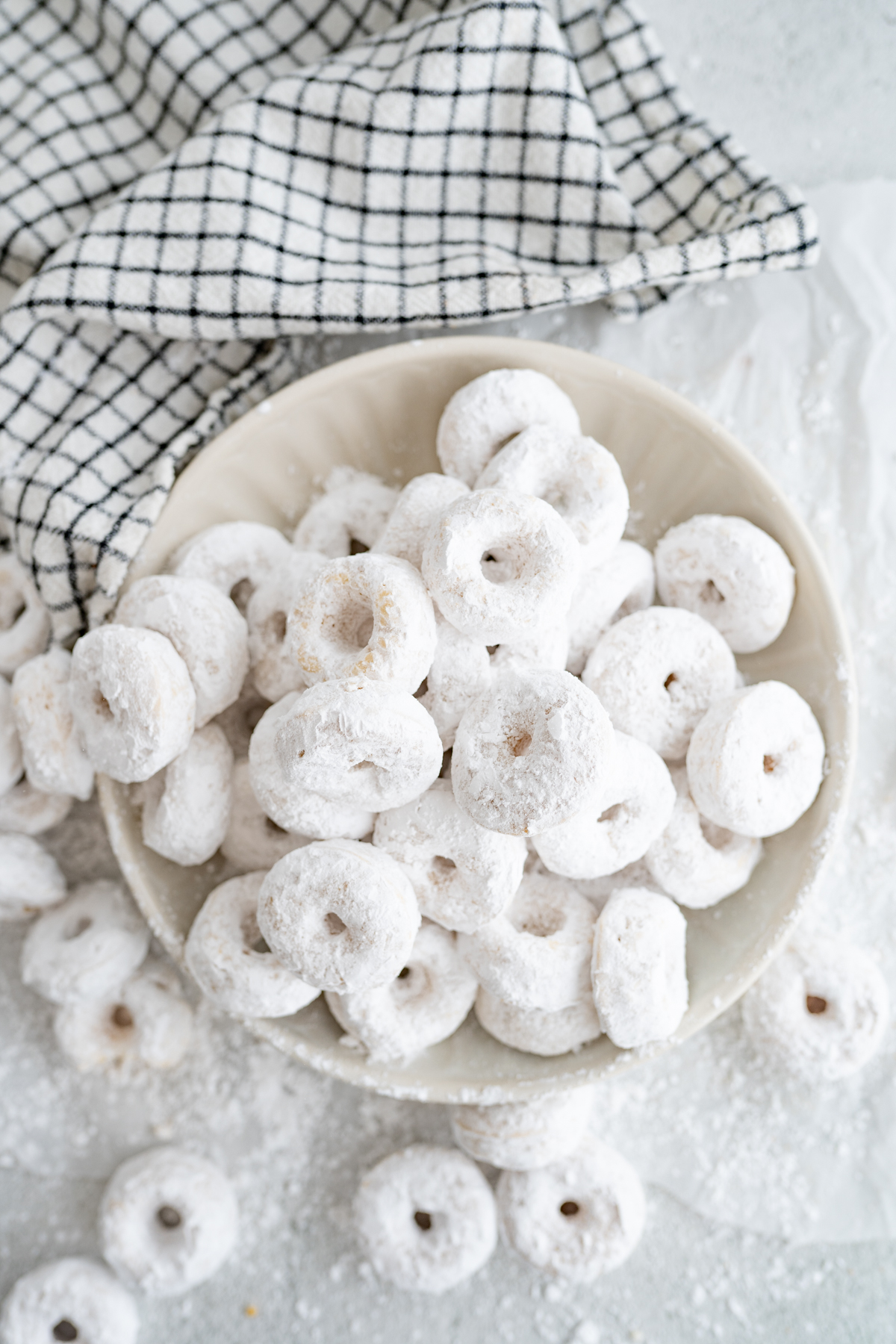 An overflowing bowl of homemade powdered sugar donuts. 